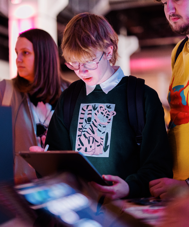 Neon lit photograph of young woman sketching on iPad while attending convention.