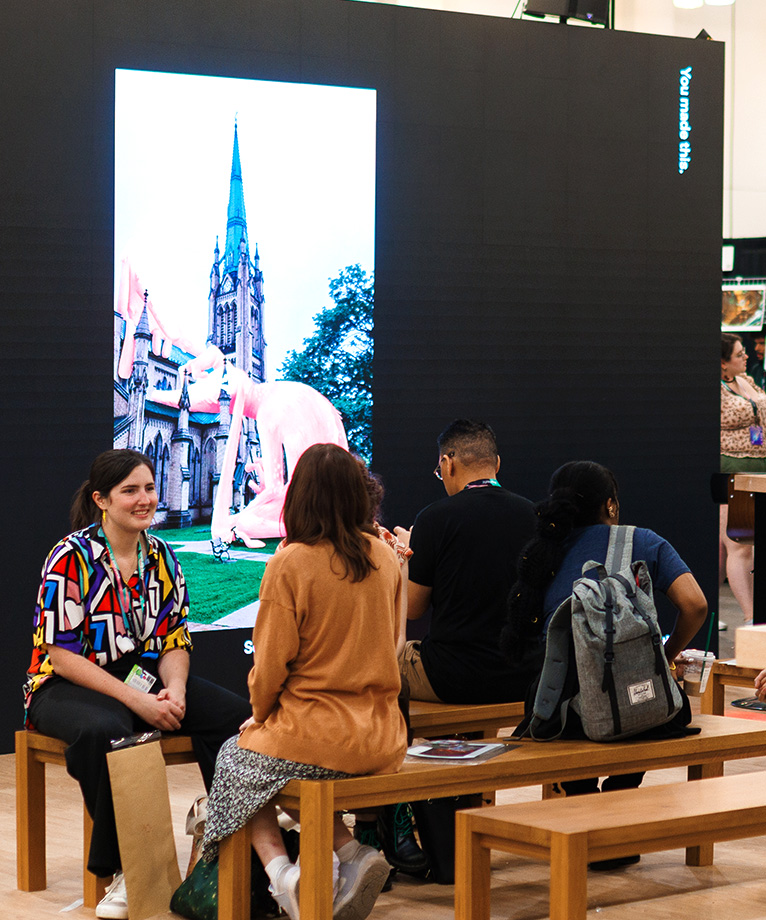 Neon lit photograph of young woman sketching on iPad while attending convention.